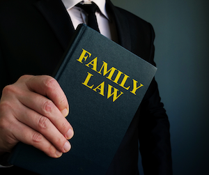 Man on black suit holding a family law book