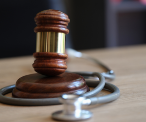 A judge’s gavel surrounded by a stethoscope.